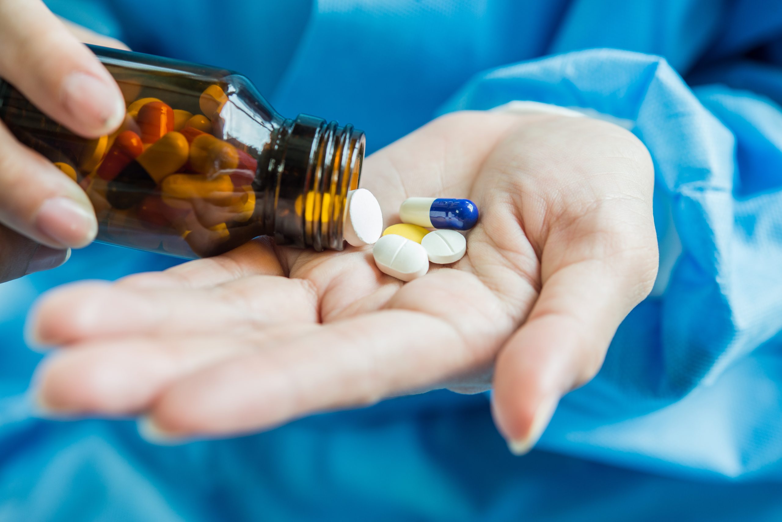 woman s hand pours medicine pills out bottle scaled